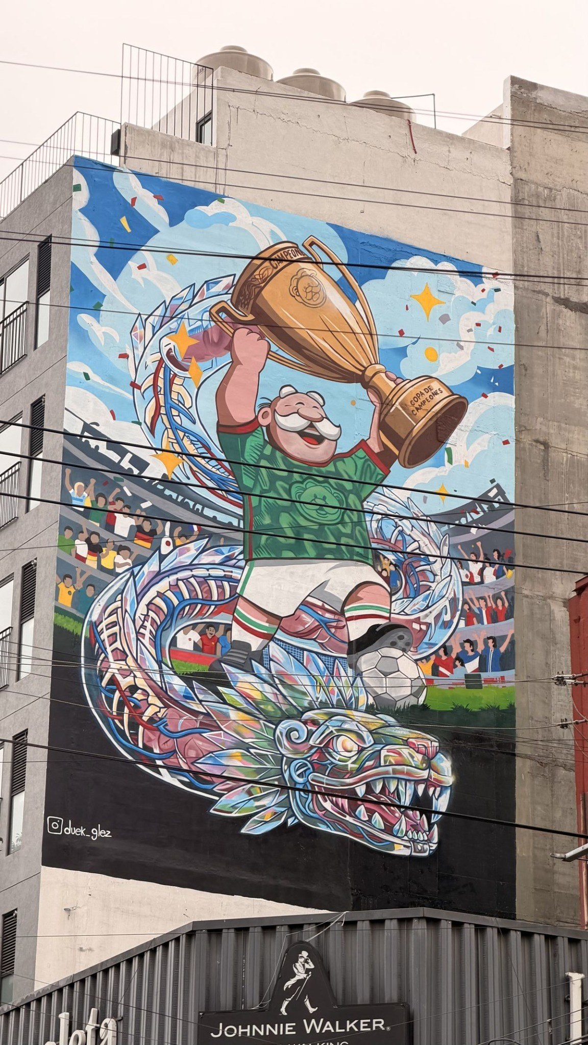 Mural callejero del Dr. Simi levantando una copa, montado sobre un Quetzalcóatl, en un edificio de la ciudad